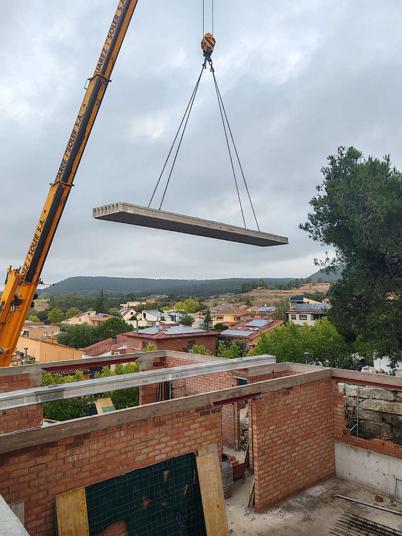 Construcció d'un habitatge a Barcelona amb una grua que transporta una estructura de formigó